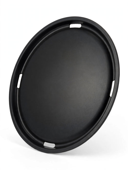 Flat round commercial Korean BBQ grill plate, angled studio view showing thin profile and vent slots